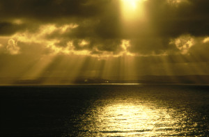 sunrays shining through dark clouds onto sea, phillip island, vic